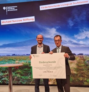 Bundeslandwirtschaftsminister Cem Özdemir übergibt den Förderbescheid für das Living Lab im Teufelsmoor an Jan Peters, Geschäftsführer der Succow Stiftung (Foto: Nina Körner/Greifswald Moor Centrum)