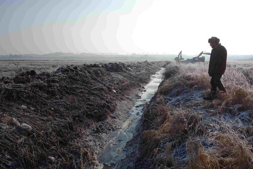 Entwässerungsgraben mit Bauarbeiten zur Wiedervernässung im Hintergrund.  Foto: Michael Succow Stiftung /F. Frucht  